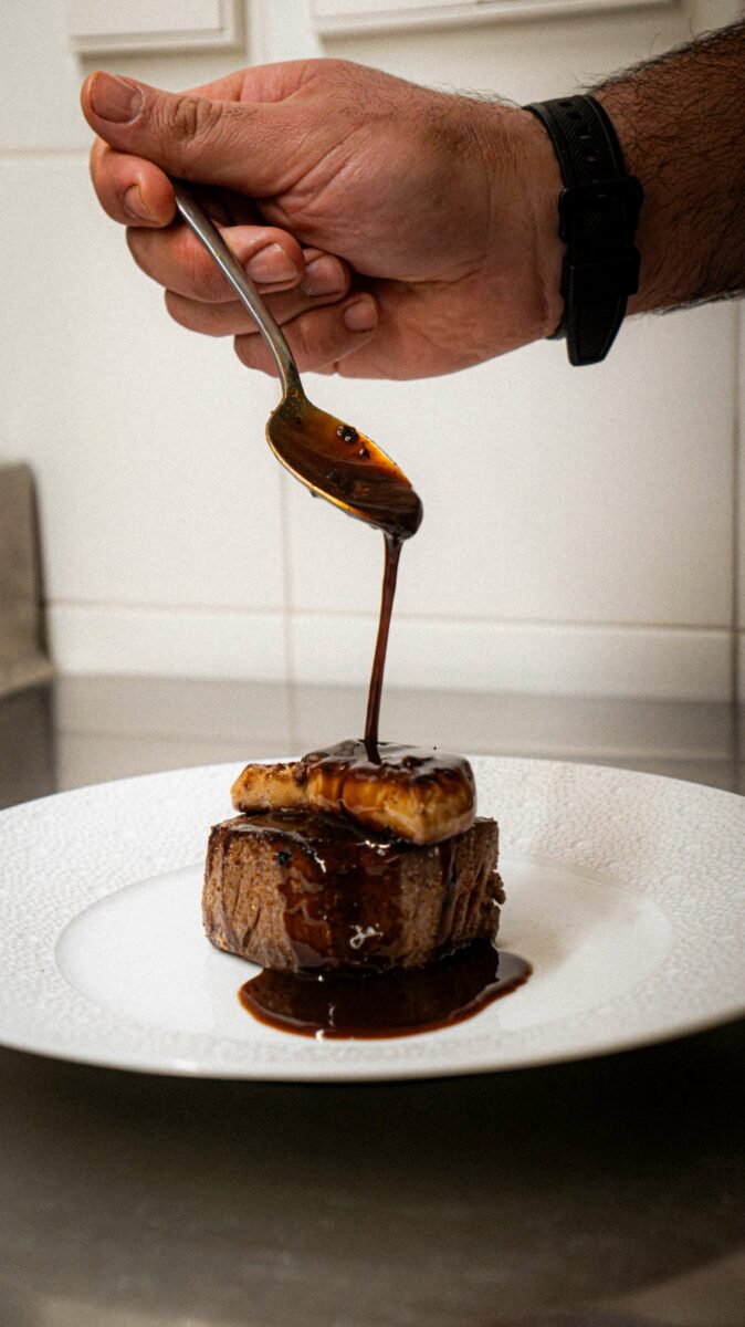 Chef bañando de salsa el solomillo con foie gras.